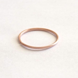May include: A simple, thin rose gold ring.