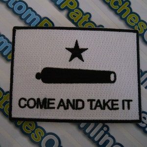 May include: White embroidered patch with a black star, cannon, and the text "COME AND TAKE IT".