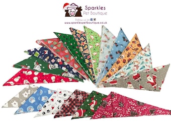 May include: A collection of triangular pet bandanas featuring various Christmas-themed patterns including Santa Claus, snowmen, gingerbread men, snowflakes, and paw prints in red, green, blue, grey, and white colours, arranged in a fan-like display.