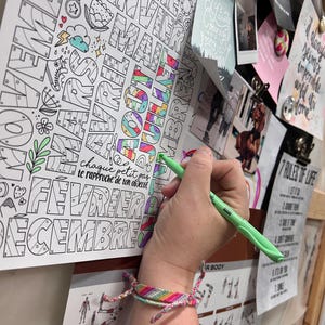 Pode incluir: Um close-up de uma m&atilde;o de uma pessoa a colorir uma p&aacute;gina de um livro para colorir com um marcador verde. A p&aacute;gina apresenta um design colorido dos meses do ano em franc&ecirc;s. O texto "chaque petit pas te rapproche de ton objectif" &eacute; vis&iacute;vel no topo da p&aacute;gina.
