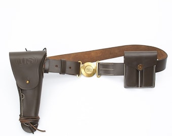 May include: A brown leather belt with a brass buckle, a holster, and a small pouch. The belt has the letters "US" embossed on the buckle and the holster.