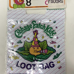 May include: A vintage Cabbage Patch Kids loot bag. The bag features a smiling character wearing a party hat, surrounded by confetti. The bag is white with diagonal red stripes and the words "LOOT BAG" in large letters.