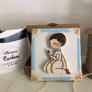 Bomboniera mattonella quadro da appendere in ceramica per Comunione con bambino in rilievo. Bordo celeste.Originale, fatto a Mano in Italia.