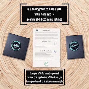 Puede incluir: Dos cajas de regalo negras con un logotipo circular flanquean una hoja de papel que detalla el cuidado de las joyas y el simbolismo de la mariposa. El papel incluye el texto "Abalone Shell" y "Jewellery Care". La imagen tambi&eacute;n incluye el texto "PAY to upgrade to a GIFT BOX".
