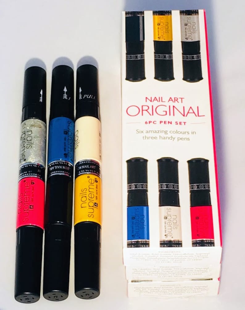 May include: A set of six nail art pens in three colors: pink, yellow, and blue. The pens are labeled "Nails Supreme" and come in a box that says "Nail Art Original 6PC Pen Set".