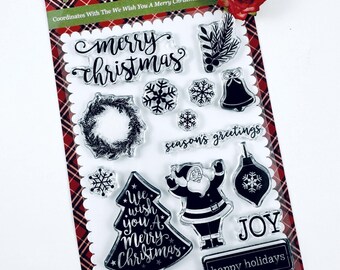 May include: A set of clear photopolymer stamps on a red and black plaid backing card. The stamps feature holiday designs including a Christmas tree with text, Santa Claus, a wreath, snowflakes, a bell, an ornament, and phrases like Merry Christmas.