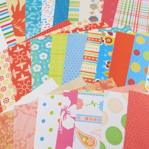 May include: A collection of rectangular paper strips featuring a variety of colorful patterns including polka dots, floral motifs, paisley, stripes, plaid, and geometric shapes in shades of red, blue, yellow, green, orange, and pink.