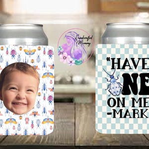 May include: Two white can coolers. One has a checkered pattern with the text "HAVE ONE ON ME -MARK". The other has a white background with a colorful insect pattern and a child's face in the center.