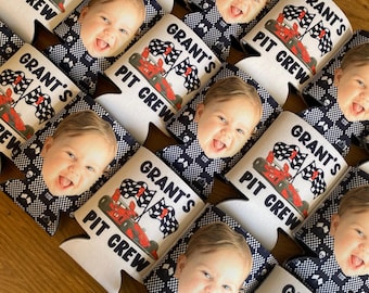 May include: A collection of white and black checkered foam can coolers featuring a printed graphic of a red race car, two checkered flags, and the text Grant's PIT CREW. Each cooler also displays a photographic portrait of a smiling baby.