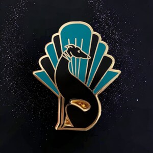 Pode incluir: Pin de esmalte preto e turquesa com uma silhueta estilizada de um galgo sentado em frente a um leque art d&eacute;co.