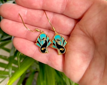 May include: Gold dangle earrings with a black and turquoise enamel design of a stylized dog in a fan shape.