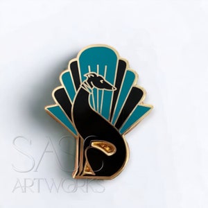 Pode incluir: Um broche de esmalte preto e dourado com um c&atilde;o galgo estilizado sentado em frente a um leque art d&eacute;co azul-turquesa e preto.