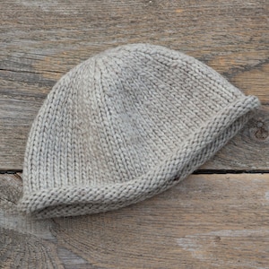 May include: A plain, light gray knitted beanie hat with a folded brim.