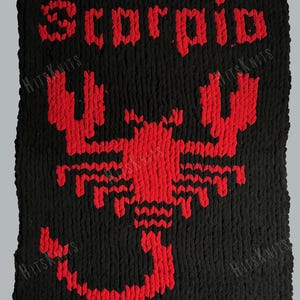 May include: A rectangular black knit blanket featuring a large red scorpion graphic centered in the middle. The word "Scorpio" is stitched in red letters above the scorpion. The texture of the yarn is thick and chunky throughout the piece.