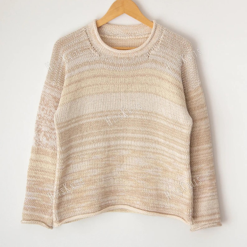 May include: A long-sleeved knit sweater featuring a crew neckline and a horizontal striped pattern in varying shades of beige, cream, and tan. The garment is displayed on a wooden hanger and includes the watermark text HUSKNITS across the fabric.