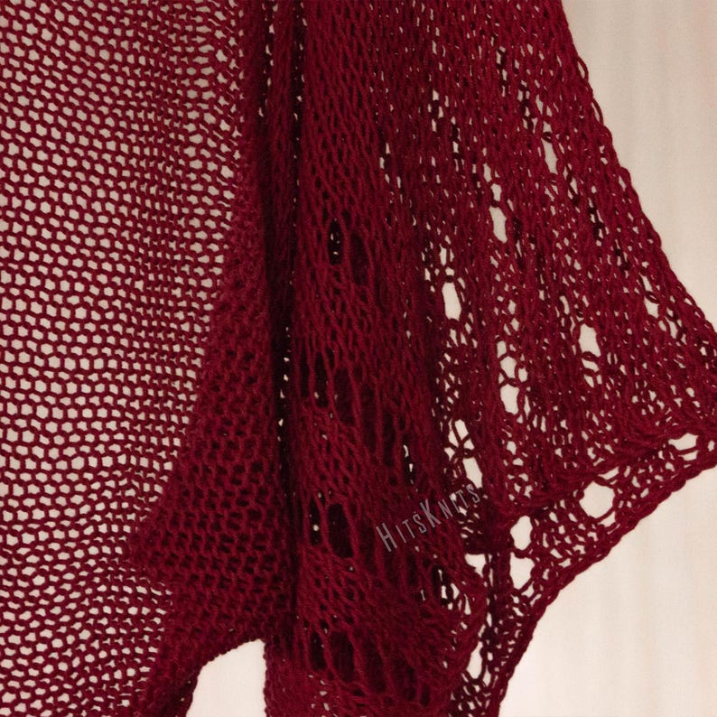 K&ouml;nnte beinhalten: Ein dunkelrotes Strickkleidungsst&uuml;ck mit einem offenen, luftigen Strickmuster unterschiedlicher Dichte. Der Stoff zeigt durchgehend einen einheitlichen dunkelroten Farbton, wobei der Text "HITSKNITS" in wei&szlig;er Schrift auf der rechten Seite zu sehen ist.
