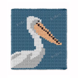May include: A knitted square with a blue background features a pelican design. The pelican is depicted in white, gray, and tan, with a long beak and a detailed pattern. The design is a close-up of the bird's head and neck.