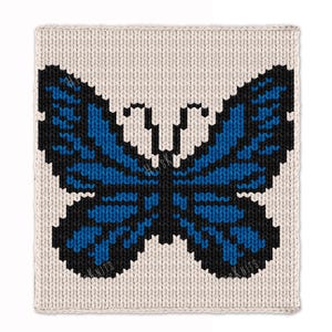 May include: A knitted square featuring a pixelated butterfly design. The butterfly has blue wings with black outlines, set against a cream-colored background. The image has a textured, handmade appearance, suggesting a craft project.