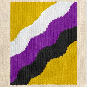 Op de afbeelding: Een vierkante gebreide vlag met diagonale strepen in geel, wit, paars en zwart. De vlag is een representatie van de non-binaire pride-vlag.