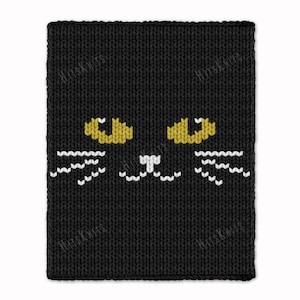 May include: Black knitted cat face design. The cat face features yellow eyes, white whiskers, and a white nose. The item is a knitted product with the text "HitsKnits" visible in the background.