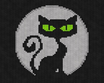 May include: Knitted black cat with green eyes on a white moon background.