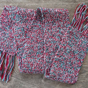 May include: A red, white, and green knitted scarf with fringe on both ends.