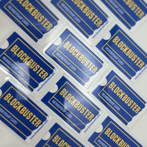May include: A collection of rectangular blue and yellow Blockbuster membership cards arranged in a grid. Each card features the Blockbuster logo in yellow text, the words Membership Card, and the website address www.blockbuster.com.