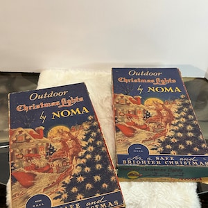 Puede incluir: Dos cajas vintage para luces de Navidad para exteriores de Noma. Las cajas son azules con un borde blanco y presentan una escena de invierno con Papá Noel y renos. El texto en las cajas dice "Luces de Navidad para exteriores de Noma" y "Para una Navidad segura y más brillante".