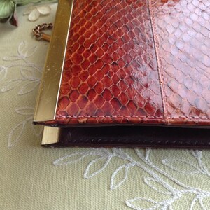 Peut inclure: Une pochette vintage en cuir de serpent brun avec un cadre en m&eacute;tal dor&eacute; et une cha&icirc;ne.