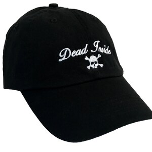 May include: Black baseball cap with a white embroidered skull and crossbones and the text "Dead Inside".