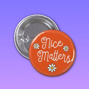 Puede incluir: Botón naranja con texto blanco que dice "Nice Matters" y tres margaritas blancas con centros amarillos.