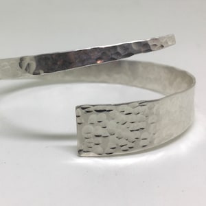May include: A silver hammered metal bangle bracelet with a unique twist design.