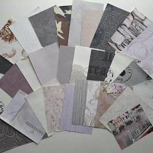 Puede incluir: Una colección de muestras de papel pintado, que muestra una variedad de texturas y patrones. Las muestras incluyen diseños florales, de piedra y abstractos en colores como gris, beige y blanco. Algunas muestras tienen detalles en relieve.