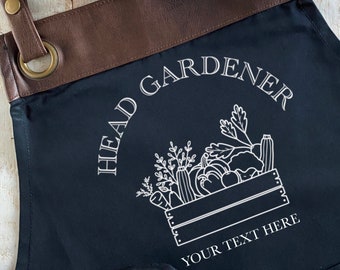 May include: Black apron with brown leather straps and a white design that says "Head Gardener" with a basket of vegetables and the text "Your Text Here".
