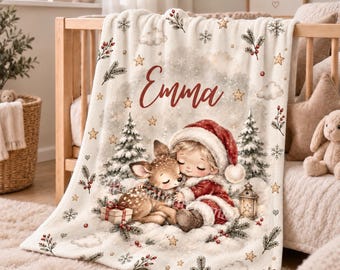 May include: A cream-colored fleece blanket featuring a festive Christmas illustration of a child in a red Santa hat hugging a small deer. The design includes pine trees, snowflakes, stars, berries, and a lantern. The name Emma is printed in red.