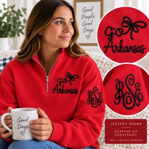 May include: A red quarter-zip sweatshirt featuring black embroidery on the chest that reads "go Arkansas" with a bow icon. The left sleeve displays a black embroidered monogram with the letters "BSE" in a script font. The fabric is red.