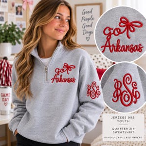 May include: A heather gray quarter-zip sweatshirt featuring red embroidery on the chest that reads "go Arkansas" with a bow graphic. The left sleeve displays a red embroidered monogram with the letters "BSE" in a decorative script font.