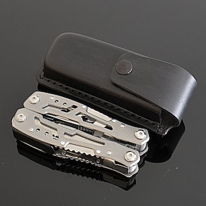 Peut inclure: Un multi-outil argent&eacute; avec divers instruments, &agrave; c&ocirc;t&eacute; d'un &eacute;tui de transport en cuir noir. Le multi-outil est en acier inoxydable et a un design compact. L'&eacute;tui a une fermeture &agrave; bouton-pression.