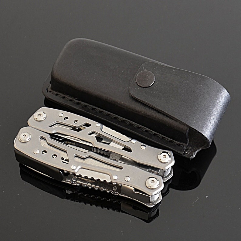 Peut inclure: Un multi-outil argent&eacute; avec divers instruments, &agrave; c&ocirc;t&eacute; d'un &eacute;tui de transport en cuir noir. Le multi-outil est en acier inoxydable et a un design compact. L'&eacute;tui a une fermeture &agrave; bouton-pression.