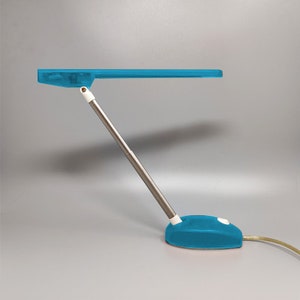 May include: A blue desk lamp with a flexible arm and a blue base. The lamp has a white switch on the base.