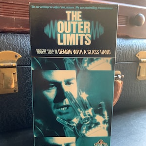 May include: A vintage VHS tape for "The Outer Limits" featuring Robert Culp in "Demon with a Glass Hand." The cover is predominantly dark blue with white and teal text and graphics. The image includes the MGM/UA Home Video logo.