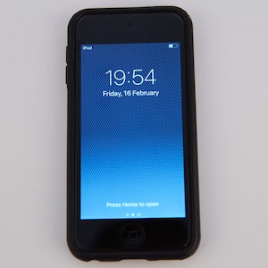 Puede incluir: Un iPod touch negro con una pantalla azul que muestra la hora 19:54 y la fecha viernes 16 de febrero. La pantalla también dice "Presiona Inicio para abrir".