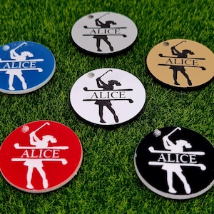 Peut inclure: Six marqueurs de balle de golf ronds avec une silhouette de golfeur et le nom "Alice" imprimé sur chacun. Les marqueurs sont de différentes couleurs : bleu, blanc, or, rouge et noir.
