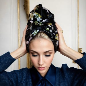 May include: A black velvet turban with floral embroidery. The turban is tied in a knot at the top and has a loose, flowing style.
