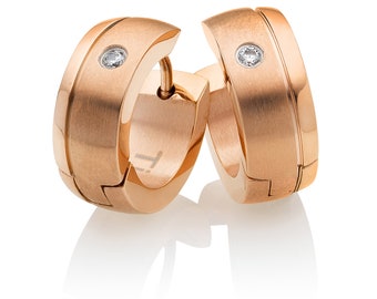 Könnte beinhalten: Ein Paar roségoldene Creolen mit gebürsteter Metalloberfläche. Jeder Ohrring hat einen kleinen, runden, klaren Edelstein. Die Ohrringe haben ein modernes, minimalistisches Design und werden auf weißem Hintergrund präsentiert.