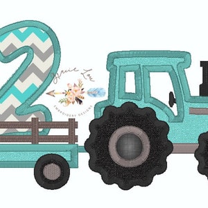 Może przedstawiać: Turkusowy traktor z numerem dwa w chevronie szarym i turkusowym z tyłu platformy. Traktor ma czarne koła z szarymi środkami.