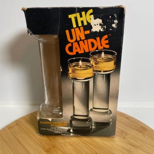 May include: A vintage "The Un-Candle" floating candle set by Corning. The box features two glass candle holders with lit candles, and the text "Floating Candle Set by Corning". The set includes two Pyrex brand candlesticks and floating wick holders.