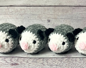 May include: Four gray and white crocheted plush toys shaped like guinea pigs with black ears and pink noses.