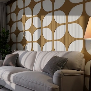 May include: A white sofa with two pillows sits in front of a wall with a geometric pattern of white circles and brown squares. A floor lamp with a brown wooden base and a white lampshade is in the corner of the room.
