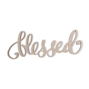 May include: A wooden sign in a cursive font that spells out the word "blessed". The sign is a light tan color with a dark brown outline, and it is set against a white background. This sign is perfect for home decor.